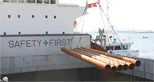 steel pipes being loaded onto a boat