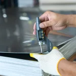 worker measuring thickness of steel sheet