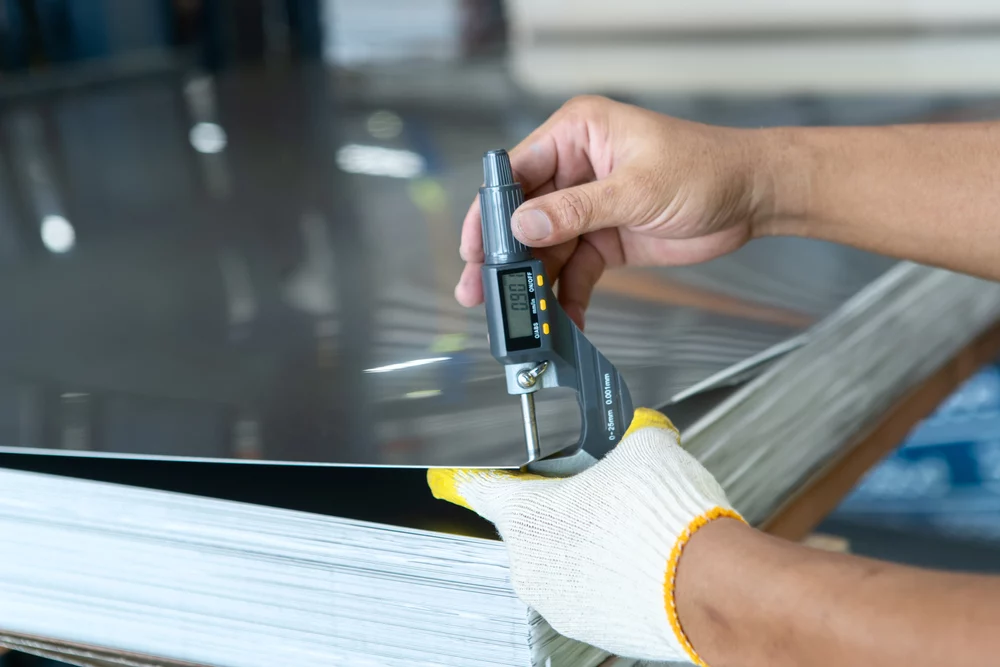 worker measuring thickness of steel sheet